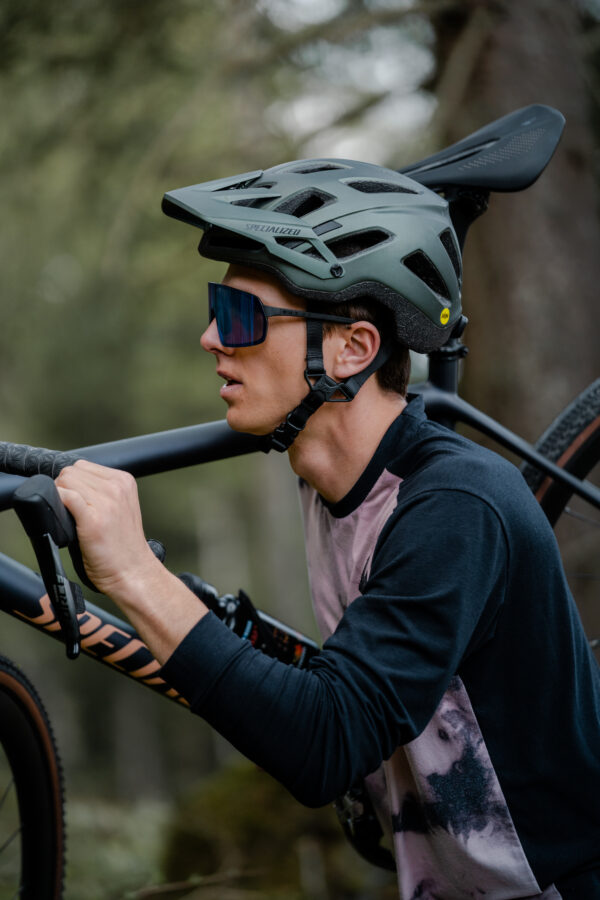 Cyclist in helmet wearing OUT OF Rams sunglasse carrying