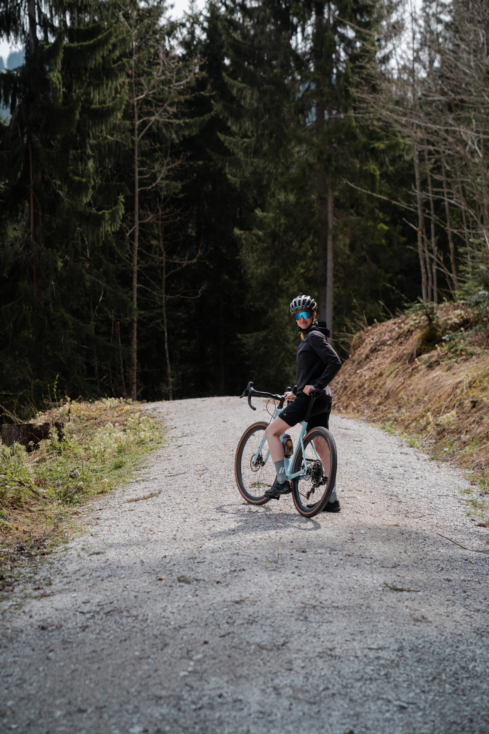 Cyclist is standing on the forest trail with his bike
